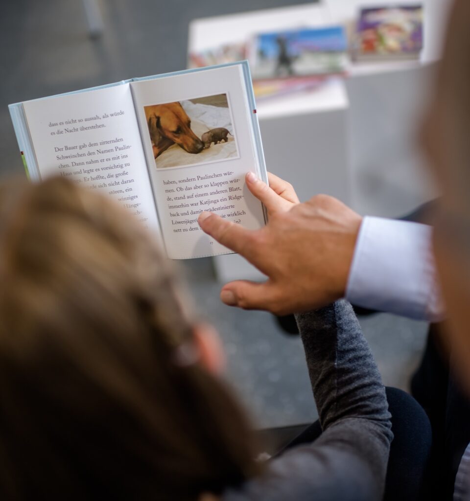 Foto von einem aufgeschlagenen Buch, das von zwei Händen gehalten wird